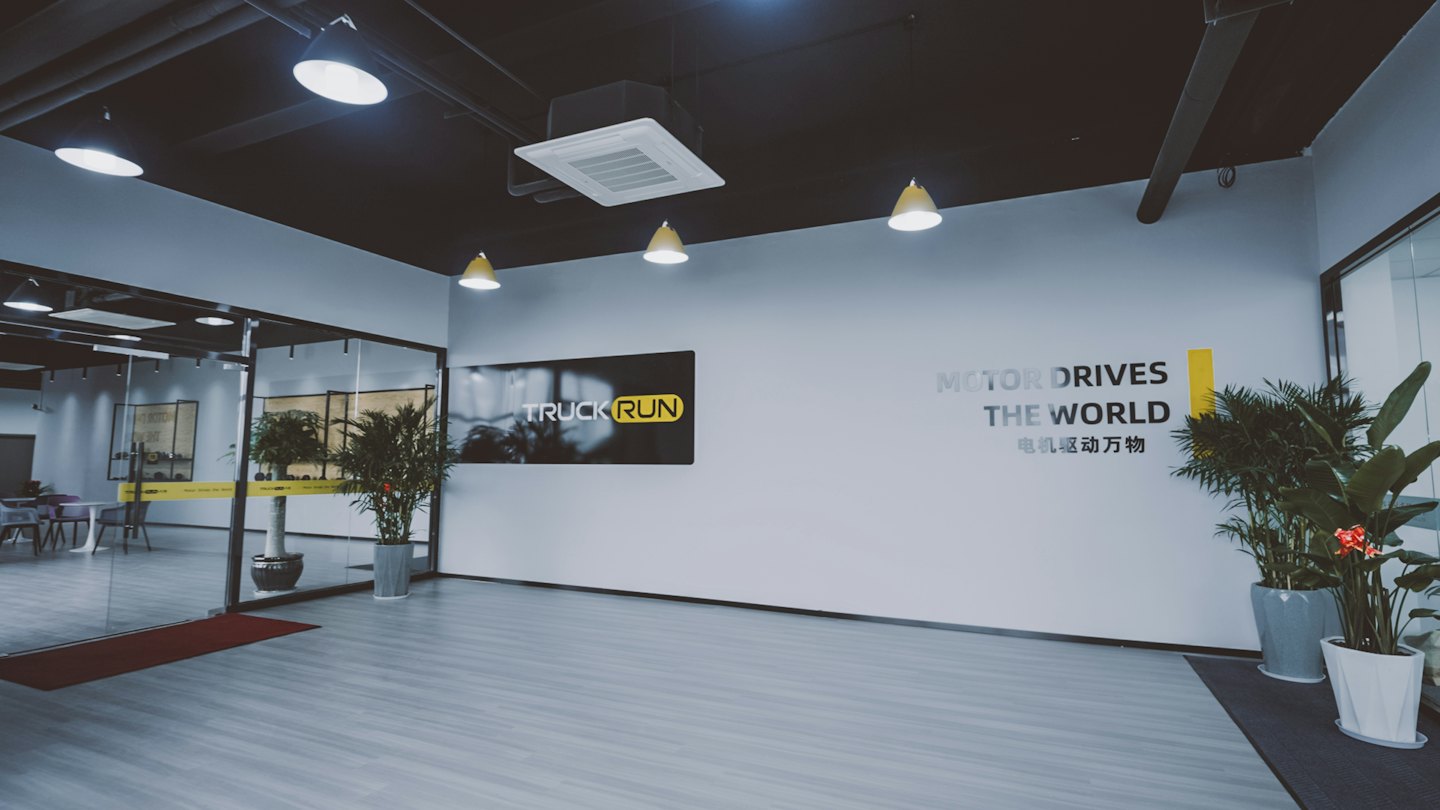 Modern office reception area with glass walls and plants.