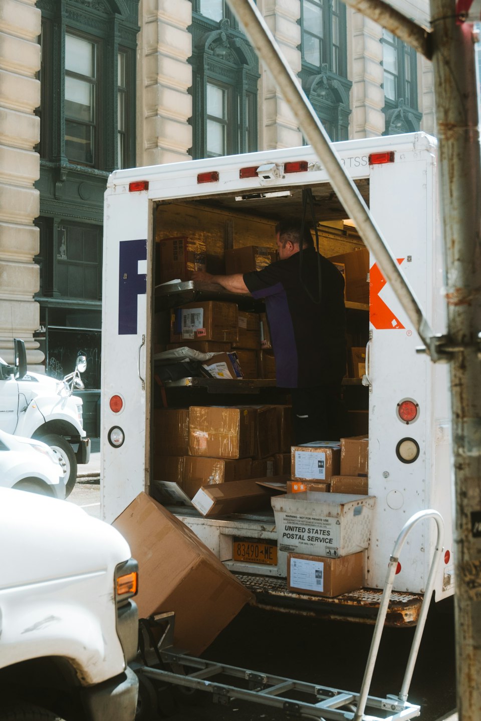 Delivery worker sorts packages in a white truck on a street.