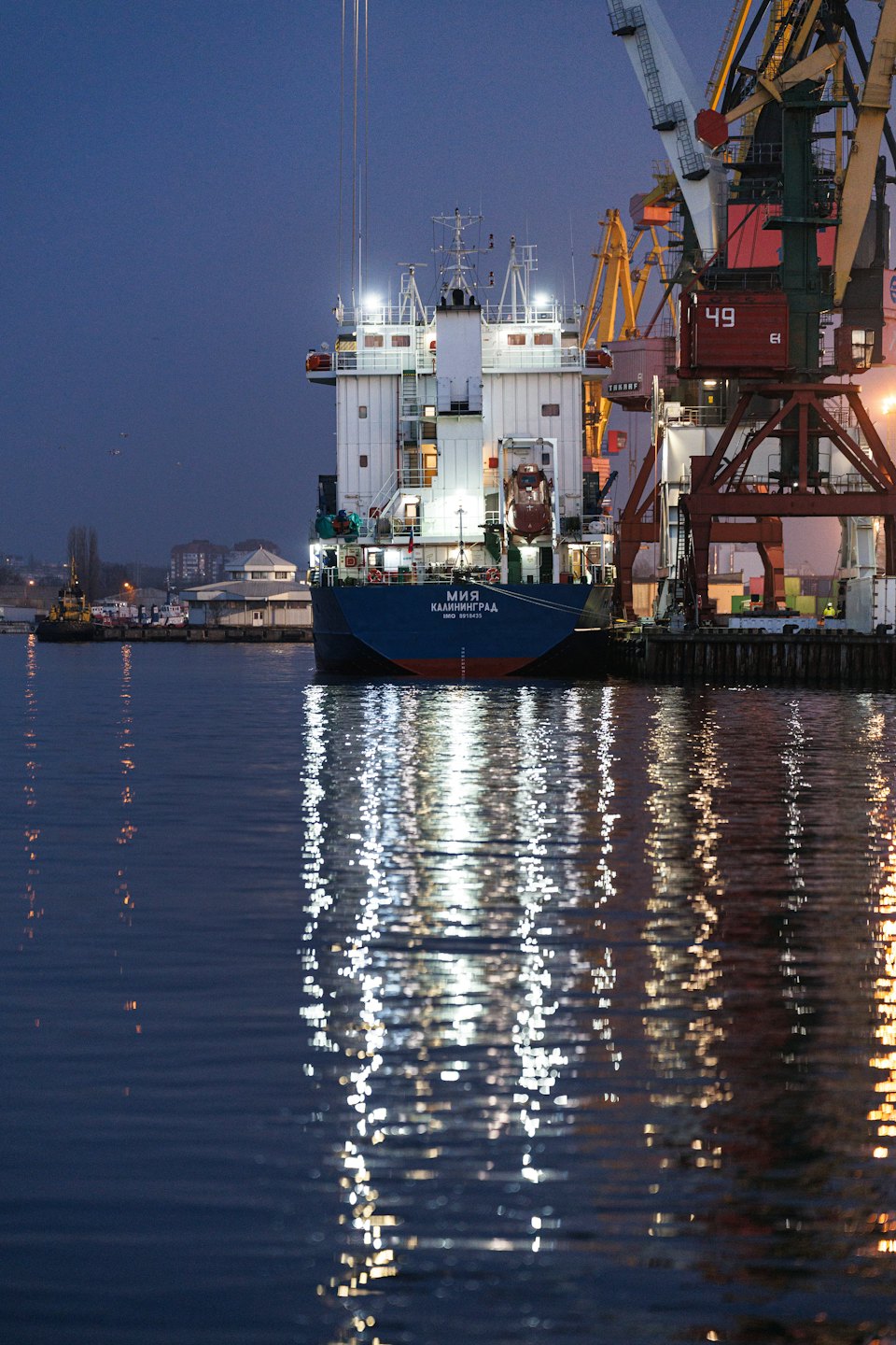 Cargo ship docked at a port with cranes.
